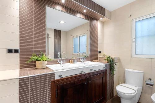 a bathroom with a sink and a toilet and a mirror at Villa Baobab - Plusholidays in Ifach