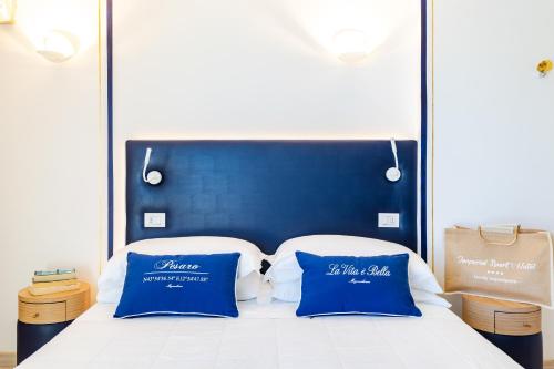 a bed with two blue pillows on top of it at UNAHOTELS Imperial Sport Hotel in Pesaro
