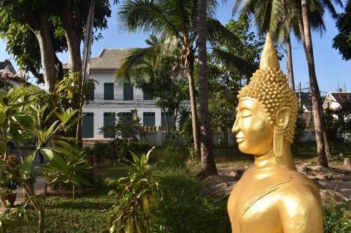 una statua d'oro davanti a una casa di PHA NYA RESIDENCE a Luang Prabang