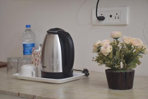 a coffee maker on a counter next to a vase of flowers at PATIALA INN in Patiāla