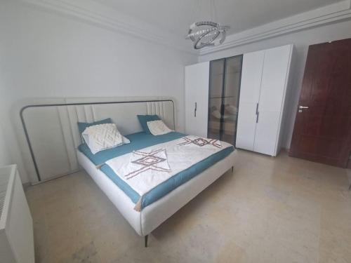 a bedroom with a bed in a white room at Appartement proche de la plage à 200 M restaurant Piccolino in Dar el Koudia