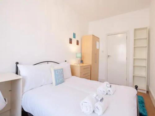 Un dormitorio con una cama blanca con toallas. en Pass the Keys Spacious 3 Bed Flat Near Kings Cross and Camden, en Londres