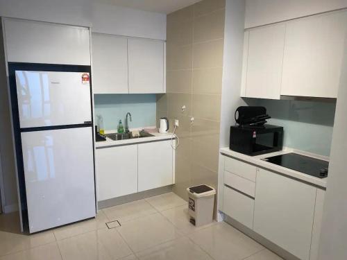 uma cozinha com armários brancos e um frigorífico branco em Sentral Suites KL Sentral by NomadNest em Kuala Lumpur