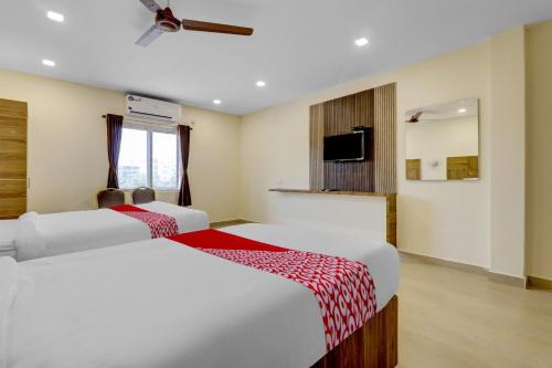 a hotel room with two beds and a tv at OYO Hotel Savitha's Grand in Vijayawāda