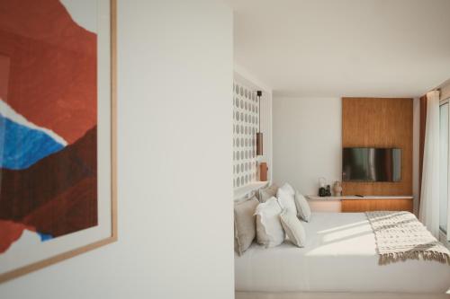 a bedroom with a white bed and a painting at H&ocirc;tel La Plage 5 &eacute;toiles La Grande Motte in La Grande-Motte