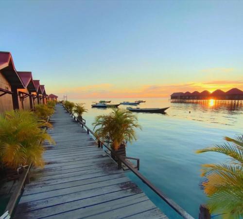 Derawan IslandsにあるFisheries VIPのヤシの木と船が浮かぶ桟橋