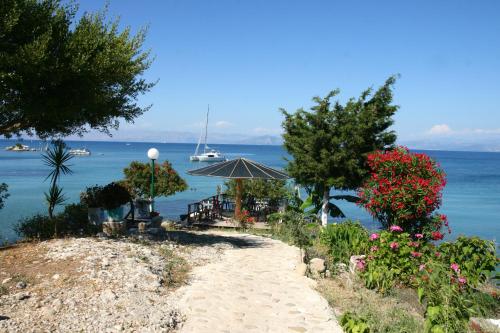 a beach with a table and an umbrella and the water at Pension Elena in Ágios Nikólaos