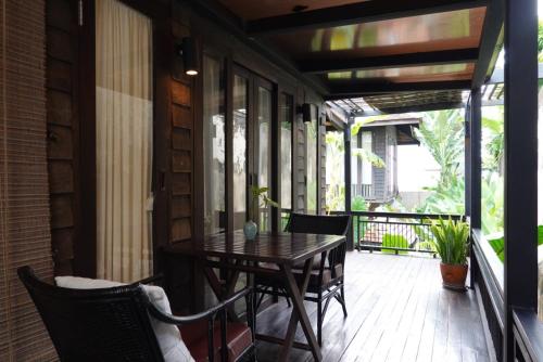 een patio met een tafel en stoelen op een veranda bij Baan Saen Fang Chiang Mai - SHA Plus in Chiang Mai