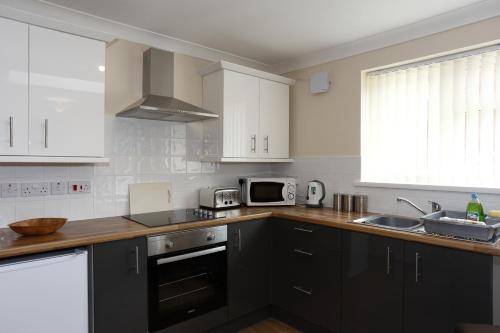 a kitchen with black cabinets and a sink and a microwave at Castle Lodge in Crosskeys