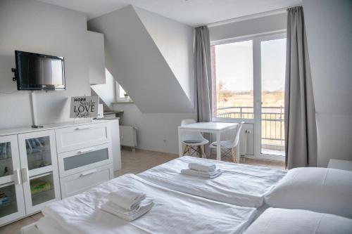 a white bedroom with a bed and a balcony at Lagunenstadt am Haff GmbH in Ueckermünde