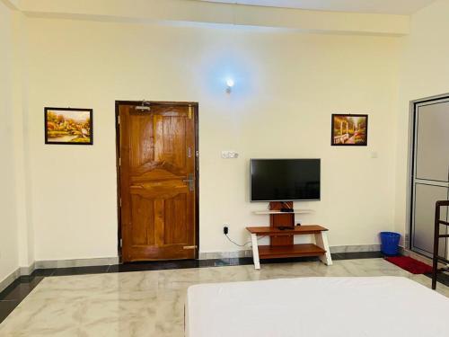 a living room with a television and a wooden door at DreamCity Hotel in Kilinochchi