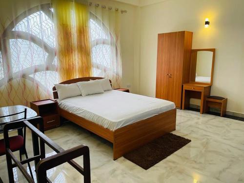 a bedroom with a bed and a mirror and a chair at DreamCity Hotel in Kilinochchi