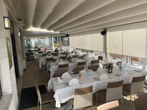 una sala da pranzo con tavoli e sedie bianchi di Hotel Firenze a Malcesine