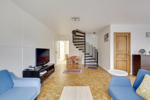 a living room with a blue couch and a staircase at La "Marquise", Jardin et Parking Privatif in Guyancourt