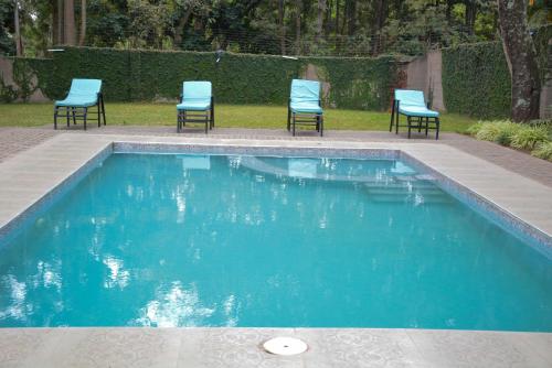 drie stoelen en een zwembad met blauwe stoelen bij 3 Degrees Hotel in Arusha