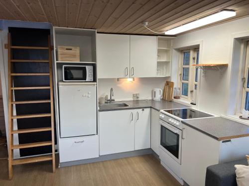 a small kitchen with white cabinets and appliances at Illu Rental - Whale View Vacation House in Ilulissat