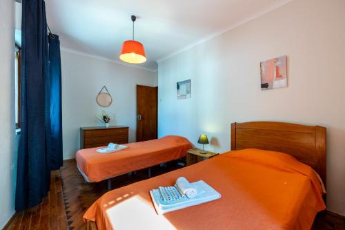 Habitación con 2 camas con sábanas de color naranja en Muralha Holiday Apartments, en Lagos