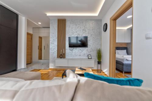 a living room with a couch and a tv on a wall at Apartman Hanah Vip Bogic in Zlatibor