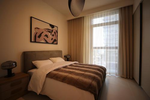 een slaapkamer met een bed en een groot raam bij Tranquil 1BR Haven in the Heart of Vista Bliss - P1AB01 in Dubai