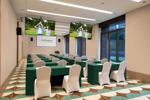 a conference room with a green table and white chairs at Somerset Chayuan Chongqing in Chongqing