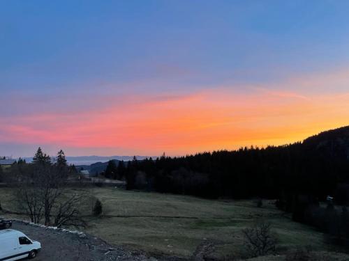 a car parked in a field at sunset at Appartement chaleureux au pied des pistes in Orbey