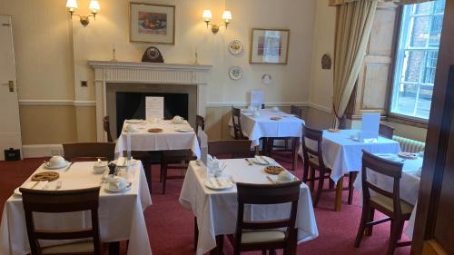 a dining room with white tables and chairs and a fireplace at Orchard Club - Newton House in Knaresborough