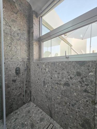 a bathroom with a shower with a window at Mykonos Suite in Paphos