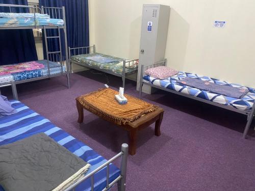 a room with three bunk beds and a table at Dream valley hostel in Abu Dhabi