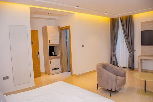 Habitación con cama, silla y TV. en Polo Grand Hotel, en Maiduguri