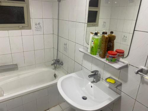 Dream valley hostel في أبوظبي: حمام أبيض مع حوض وحوض استحمام