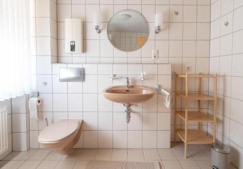 La salle de bains est pourvue d'un lavabo, de toilettes et d'un miroir. dans l'établissement Haus Elfriede, à Niedermennig