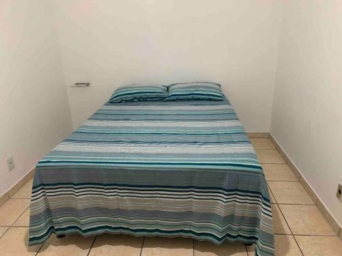 a bed in a room with a striped blanket on it at Apartamento Jardim Camburi 2 quartos in Vitória