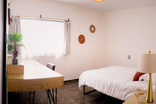 sypialnia z 2 łóżkami, biurkiem i oknem w obiekcie Casa Amma - D w mieście Matehuala