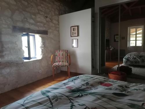 um quarto com uma cama, uma cadeira e uma janela em Chez Yvette & Shoji em Mauvezin