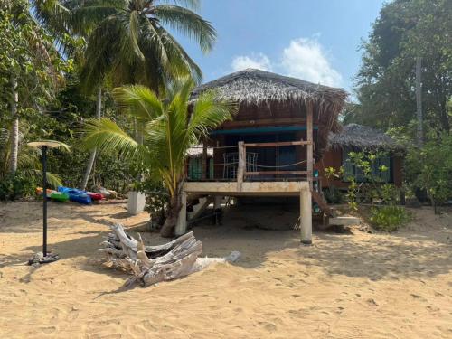 een huis aan het strand met een palmboom bij Sunset Beach Bungalow Koh Pu in Ko Jum