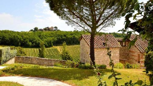 un jardín con un edificio de ladrillo y un árbol en Les Hauts de Broze, en Broze