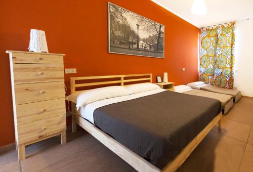 a bedroom with two beds and a dresser and orange walls at Guest House Parco del Mulino in Livorno