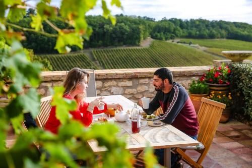 Un hombre y una mujer sentados en una mesa comiendo comida en Les Hauts de Broze, en Broze