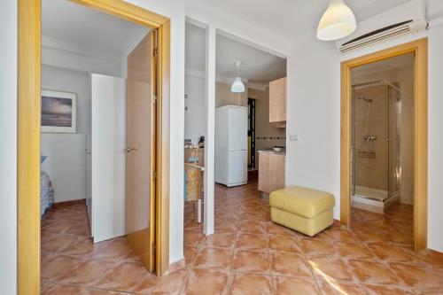 a living room with a yellow stool and a kitchen at Apartamento frente a la playa in Málaga