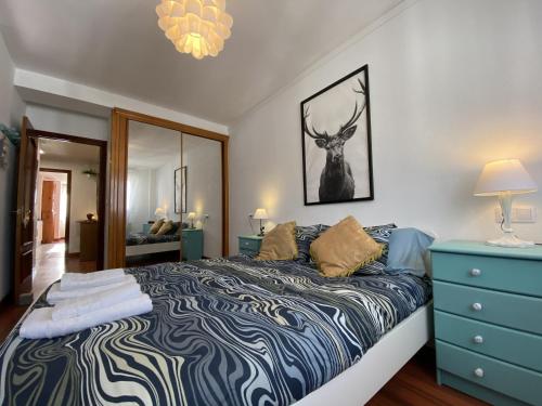 a bedroom with a bed with a blue dresser and a mirror at Apartamento Cleo Gijón in Gijón