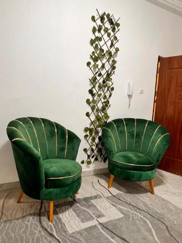 two green chairs sitting next to each other in a room at Appartement meublé au virage in Yof