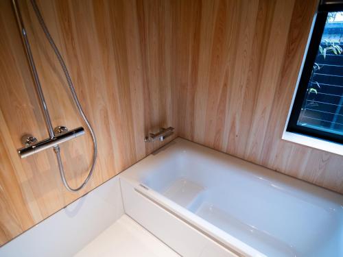 a bath tub in a bathroom with a window at Auberge Homachi Mikuniminato in Sakai