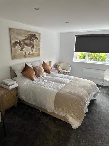 1 dormitorio con 1 cama y una pintura de un caballo en Poppy Lodge faversham en Boughton Street