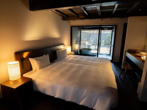 a bedroom with a large white bed and a window at Auberge Homachi Mikuniminato in Sakai