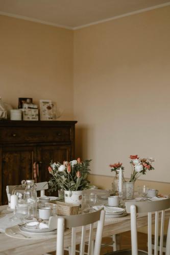 a dining room table with plates and flowers on it at Belcasale in Vignale Monferrato