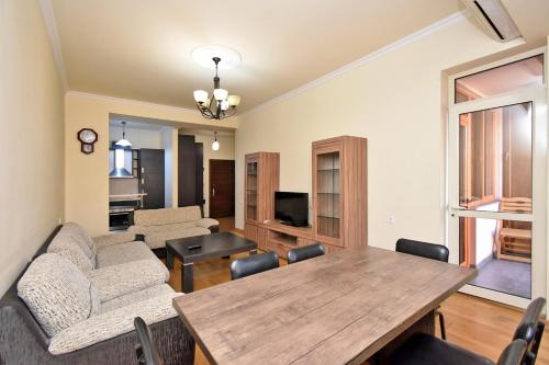 sala de estar con mesa de madera y sillas en Rent Inn Yerevan on Buzand Street, en Ereván