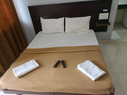 a bed with two slippers and a remote control on it at Hotel Popillon, Kolhapur in Kolhapur