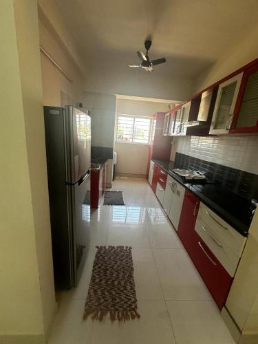uma cozinha com um frigorífico preto e armários vermelhos em Garden Club em Mangalore