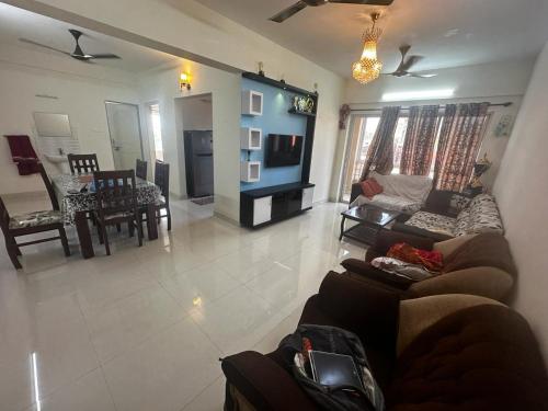 uma sala de estar com um sofá e uma televisão em Garden Club em Mangalore
