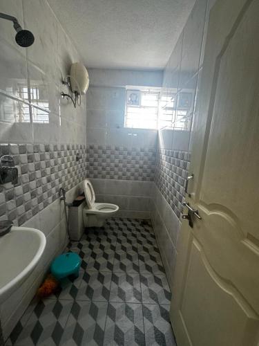 uma casa de banho com um WC branco e um lavatório. em Garden Club em Mangalore